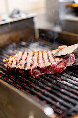 cooking beef steak on grill in restaurant kitchen