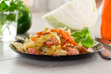 cooked fried cabbage with vegetables and sausages