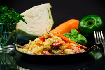 cooked fried cabbage with vegetables and sausages