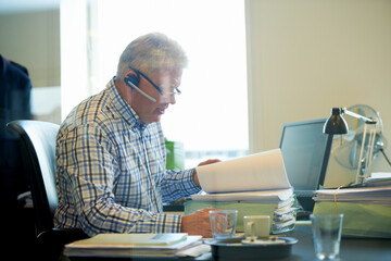 Senior businessman, documents and headphones in call center for communication or online advice at...