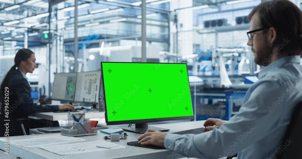 Poster Two Industrial Software Engineers Working at a Modern Factory. Male Using a Desktop Computer with Green Screen Mock-Up Display. Technological Facility with Robotic Arms in the Assembly Hall