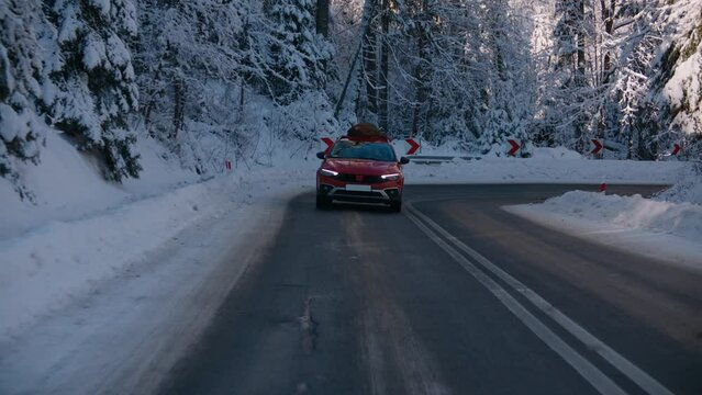 TRACKING Family driving home with a Christmas tree tied to a roof of a generic red car against beautiful mountain landscape