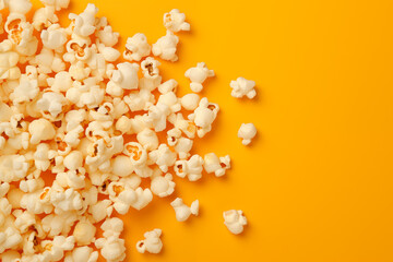 Popcorn scattered on a yellow background.  A classic movie theater snack. View from above.