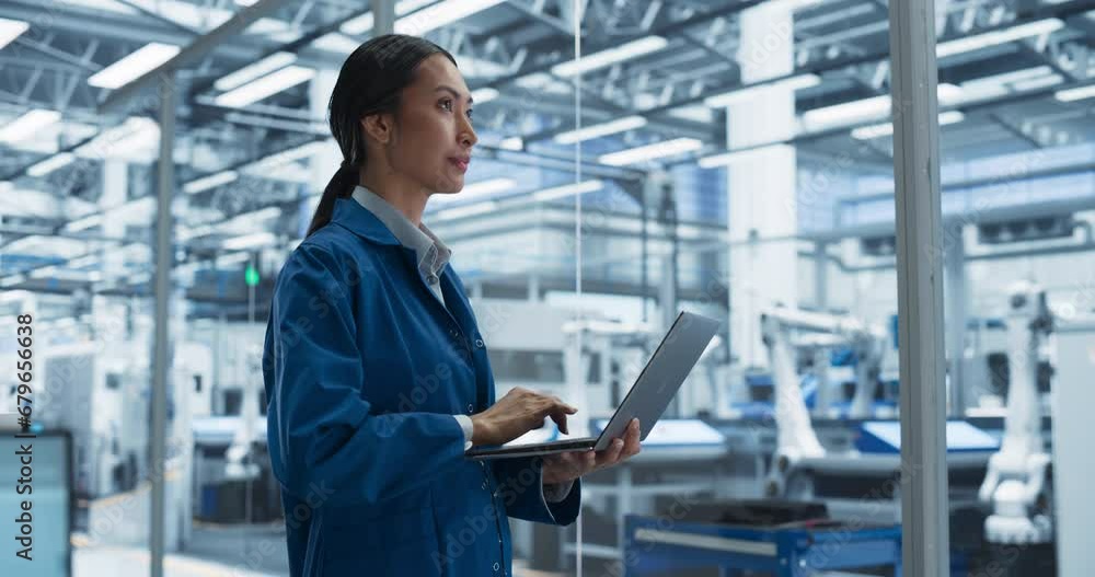 Poster Portrait of a Beautiful Electronics Manufacturing Technician Working on a Laptop Computer at a Factory. Asian Female Specialist Developing, Maintaining, Setting Up Programs for Machine Production
