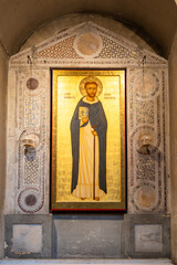 Medieval catholic saint portraited on a  golden background decorating ancient stone wall inside old church in Italy