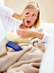 Horror, popcorn and woman on couch watching tv with remote, blanket and streaming movies in home....