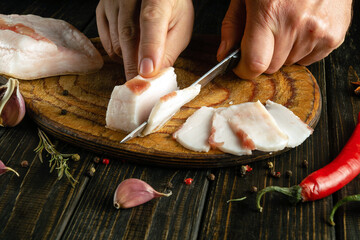 The process of preparing sandwiches for a snack from lard and garlic in the kitchen. Chef hands use...