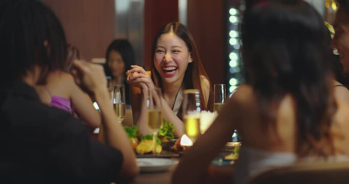Beautiful Asian woman is Relishing a Delightful Dinner with Friends at a Bar, Immersed in the Joy of a Vibrant Night Party. They Enjoying with Night Party Together. Party and Celebration Concept.