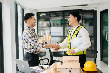 Construction team shake hands greeting start new project plan behind yellow helmet on desk in office