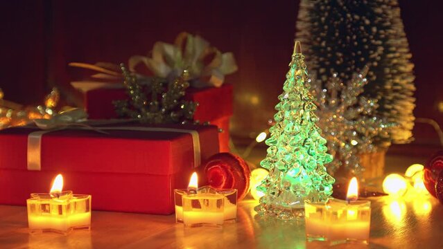 Red gift box and candlelight on a wooden table for Christmas and New Year.