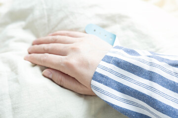 Close-up of patient's hands on hospital bed