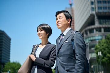 ビジネス街を歩く50代男性会社員と30代女性会社員