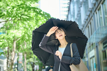 日傘を差して歩く30代女性会社員