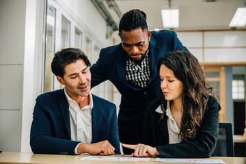 CEO and diverse team in a meeting, planning, and analyzing documents and graphs for research. Multicultural professionals exemplify teamwork and diversity. Teamwork