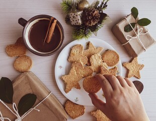  hand picking up gingerbread and butter christmas cookies on rustic background