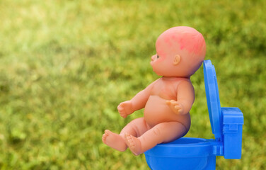 baby doll Sitting On A Potty. teaching child to potty train. Concept for the child doesn't want on...