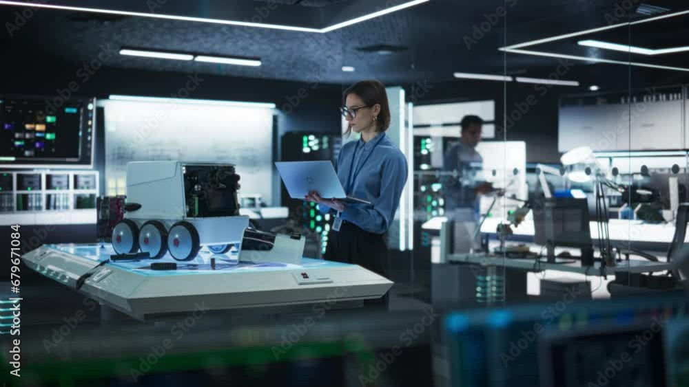 Poster Portrait of a Female Technical Specialist Working in High Tech Research Laboratory with Modern Equipment: Female Developer Using Laptop to Write Code for an Advanced-Technology Delivery Robot