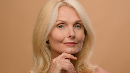 Portrait beautiful old woman perfect face mature Caucasian senior middle age female in beige studio...