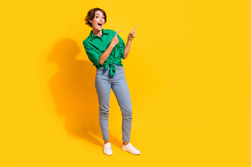 Full length photo of funky excited girl dressed green shirt pointing two fingers empty space...