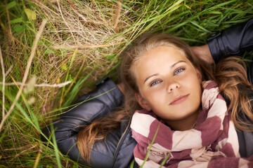Serious, portrait and woman relax on grass in nature, countryside or field in environment. Above,...