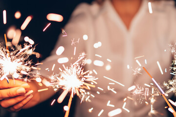 Close up of a hands holding some sparklers celebrating the new year - obrazy, fototapety, plakaty