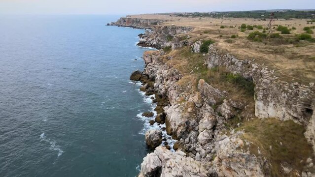 Aerial drone footage of cinematic azure blue-green turquoise waves in Bulgaria crashing on scenic sea cliffs and rocks