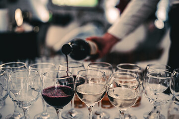 waiter pouring red wine from bottle into a glass in cafe or restaurant