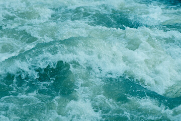 Water splash with bubbles. Defocus blurred transparent blue colored clear calm water surface texture with splashes reflection. Trendy abstract nature background. Water waves in sunlight.