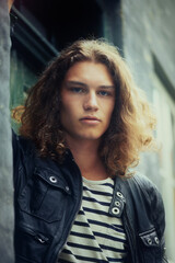 Fototapeta premium Man, portrait and serious outdoor for fashion, urban style and edgy outfit with confidence and pride. Person, face and young model with casual jacket, long hairstyle and stylish with calm expression