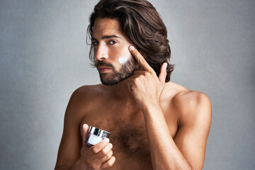 Portrait, skincare or lotion with the face of a man in studio on a gray background for his grooming...