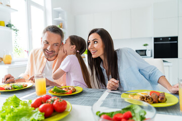 Photo of good mood tricky wife husband little girl telling secrets eating food indoors apartment kitchen