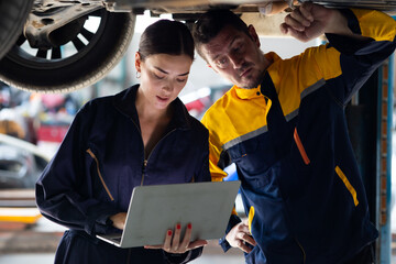 apprentice. Caucasian Female trainee Mechanics Working Underneath Car with male Instructor at Car maintenance and auto service garage. Car maintenance and auto service garage concept. - obrazy, fototapety, plakaty