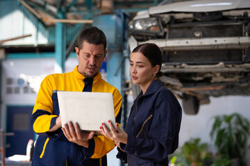 Portrait woman apprentice. Caucasian Female trainee Mechanics Working Underneath Car with male Instructor at Car maintenance and auto service garage. Car maintenance and auto service garage concept.
