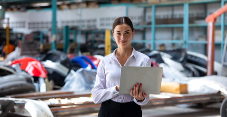 Small business owner. Caucasian business woman holding laptop computer standing at Car maintenance and auto service garage. Car maintenance and auto service garage concept. - obrazy, fototapety, plakaty