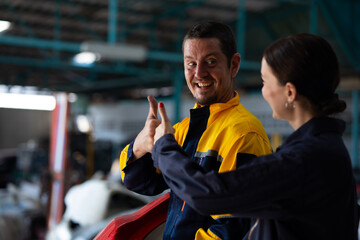Unity and teamwork apprentice. Caucasian Female trainee Mechanics Working Underneath Car with male...