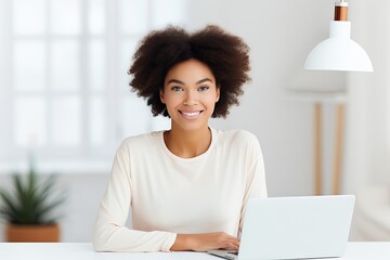 Confident young African American woman in a modern office working on her laptop with a cheerful and professional demeanor.