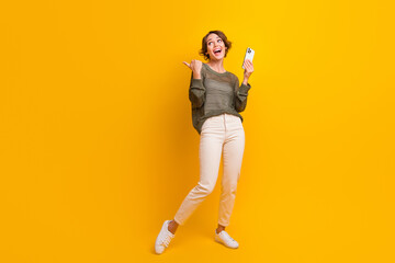 Fototapeta na wymiar Full length photo of cheerful lovely blogger girl wear trendy clothes look up empty space isolated on yellow color background