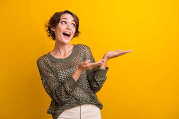 Photo of surprised amazed girl looking up empty space presenting novelty offer isolated on vivid...
