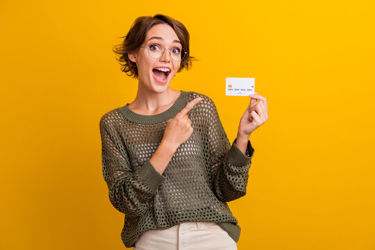 Photo portrait of attractive young woman hold point credit card wear trendy knitwear khaki clothes isolated on yellow color background