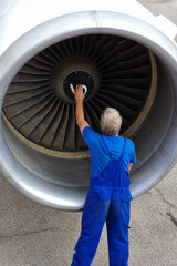 technician inspecting airplane engine on airport track