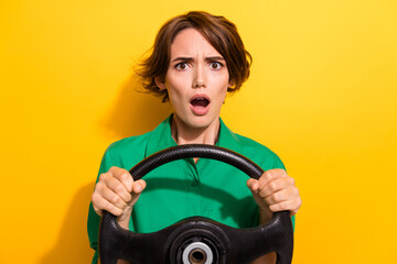 Fototapeta na wymiar Photo of shocked scared girl dressed green shirt driving auto open mouth isolated yellow color background