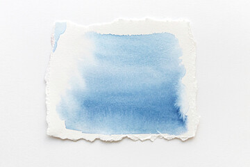 White Ripped Piece of Paper with watercolor blue streaks isolated. Top View of Blank Adhesive Paper...