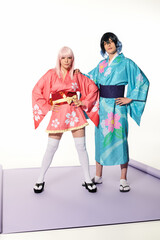 confident expressive couple in colorful kimonos and wings posing with hands on hips, cosplay trend