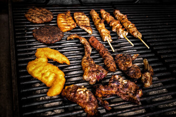 Sizzling close-up of a diverse meat mix grilling to perfection. Assorted meats cooking on the barbecue, capturing the essence of outdoor culinary delight