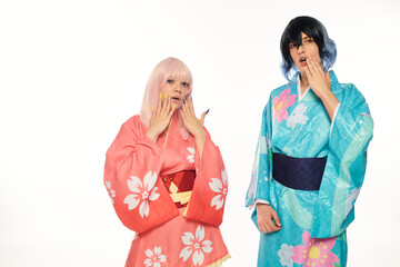 astonished anime couple in colorful kimonos and wigs touching faces on white, cosplay trend