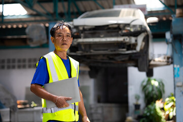 Portrait senior Asian thai male professional mechanic repairs car working in garage. Car...