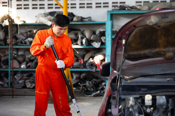 scissor jack. Asian thai or chinese male mechanic repairs car in garage. Car maintenance and auto service garage concept