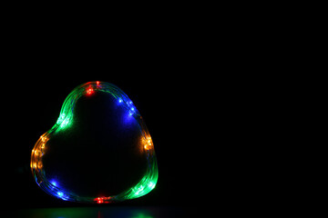 Corazón sobre fondo negro con luces de colores. Espacio para texto al lado derecho.