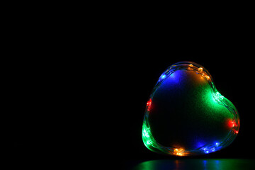 Corazón sobre fondo negro con luces de colores. Espacio para texto al lado izquierdo.