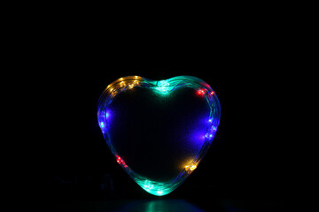 Corazón sobre fondo negro con luces de colores.